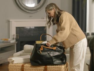 Senior woman packing a bag in a cozy living room, preparing for moving out.