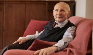 Senior man sitting comfortably on a sofa in a warm and inviting living room.