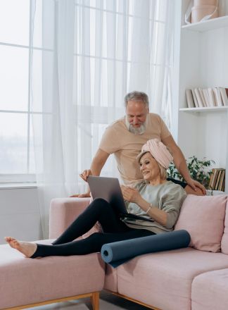 Happy senior couple enjoying leisure time at home using a laptop on the sofa.